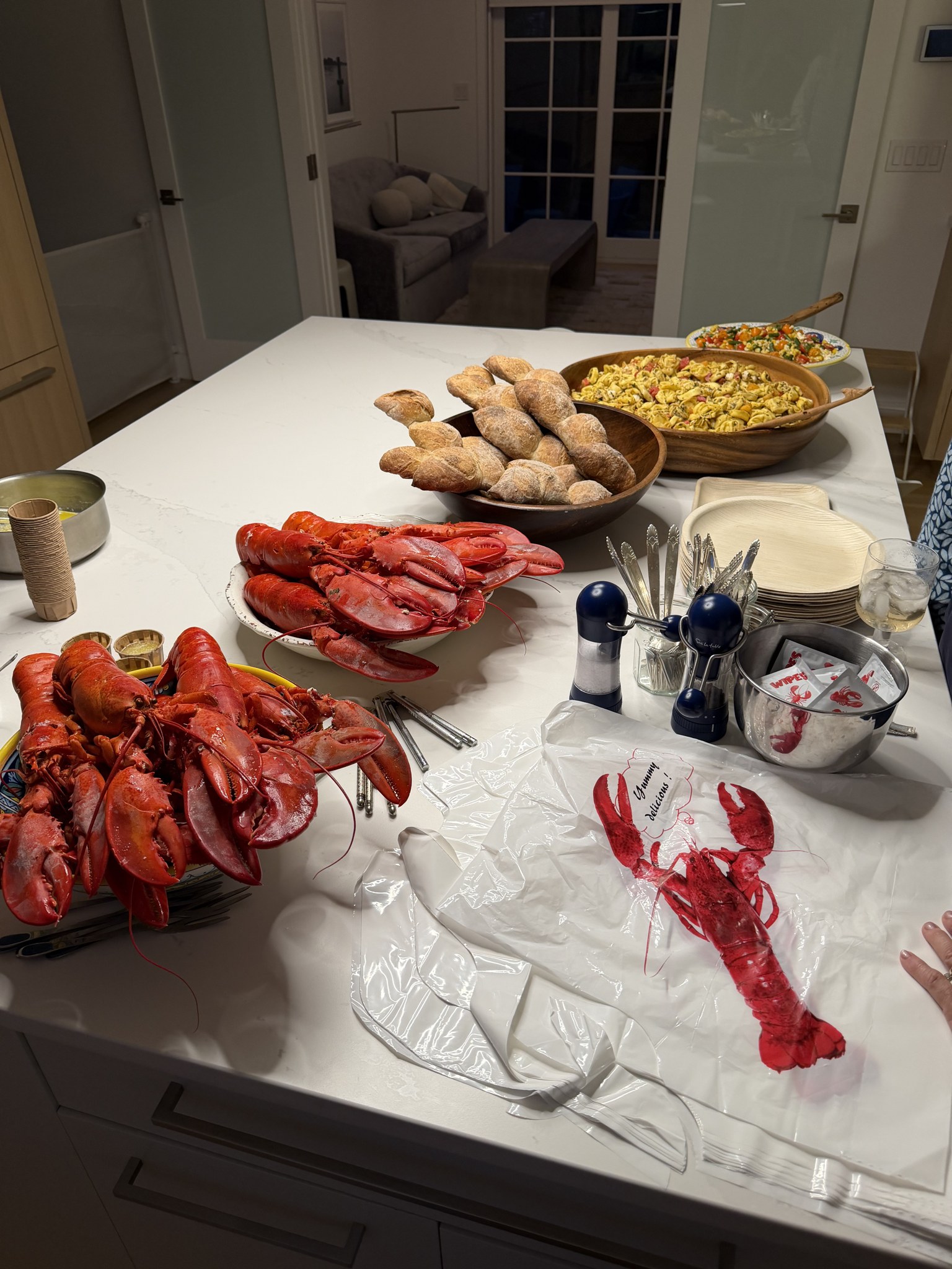 A lobster dinner spread with bread and pasta salad on a marble island